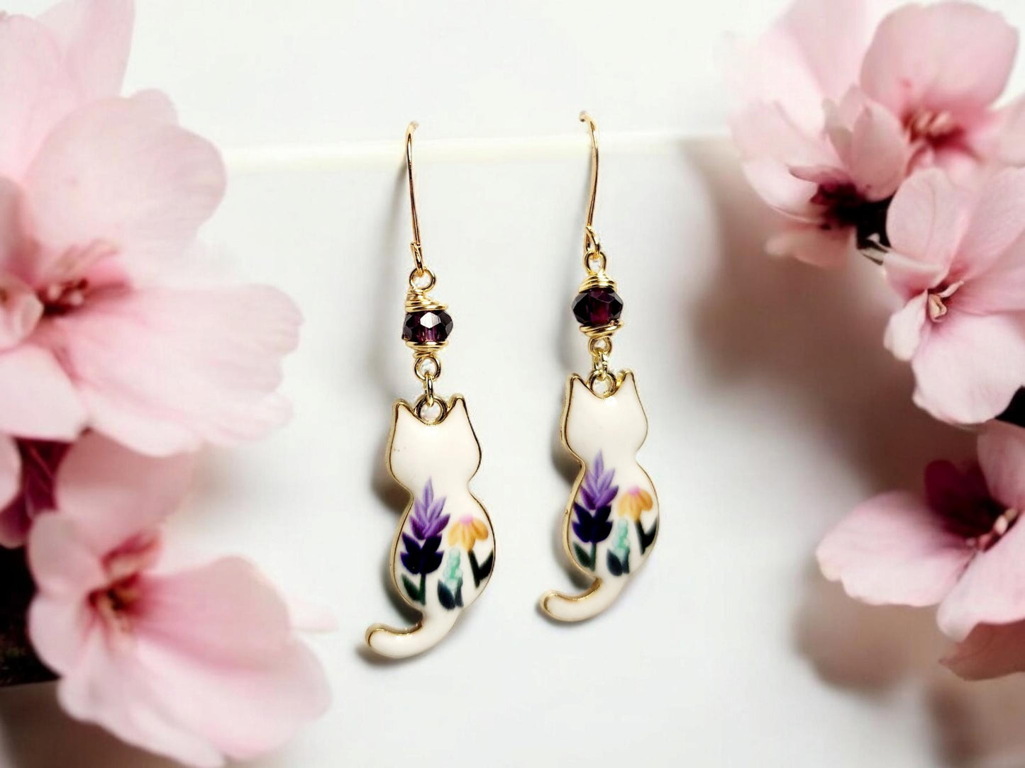 White cat charm dangle earrings with purple and yellow painted flowers and purple glass beading.