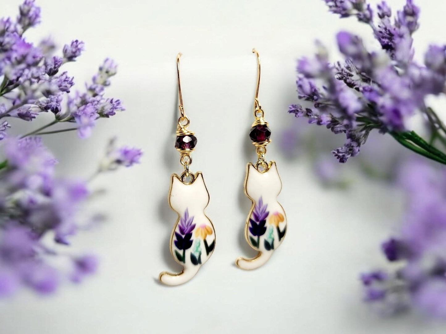 White cat charm dangle earrings with purple and yellow painted flowers and purple glass beading.