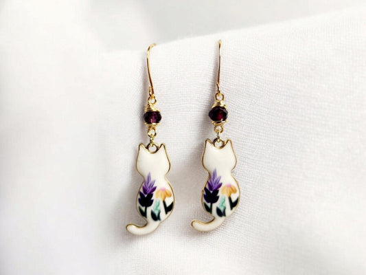 White cat charm dangle earrings with purple and yellow painted flowers and purple glass beading.